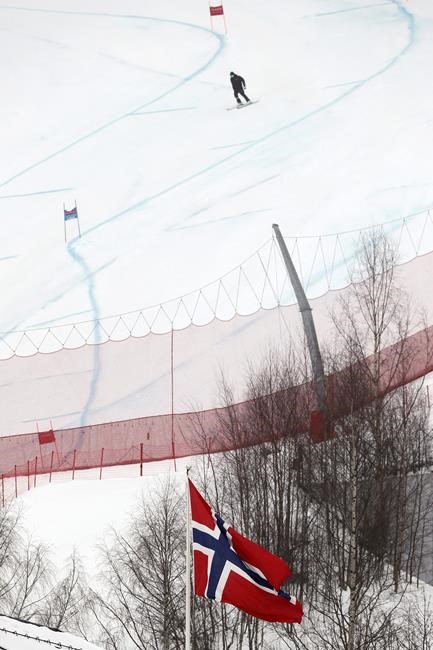 A Norwegian flag waves as a race official comes down the course after an alpine ski, men's World Cup super-G was cancelled due to bad weather, in Kvitfjell, Norway, Sunday, March 8, 2020. (AP Photo/Gabriele Facciotti)