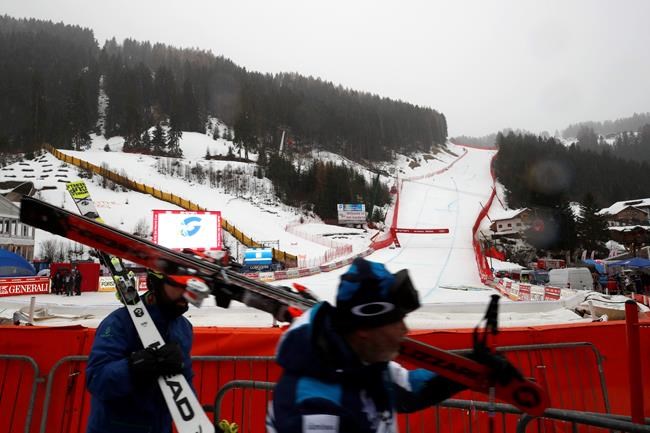 Skiers carry their skiis after an alpine ski, men's World Cup downhill was canceled due to bad weather, in Val Gardena, Italy, Saturday, Dec. 21, 2019. (AP Photo/Gabriele Facciotti)