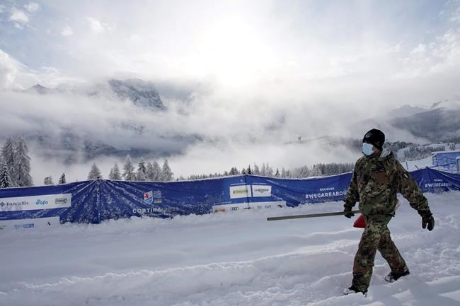 An Italian army soldier helps clear the course after a women's alpine combined race was canceled due to heavy snowfall, at the alpine ski World Championships in Cortina d'Ampezzo, Italy, Monday, Feb. 8, 2021. (AP Photo/Giovanni Auletta)
