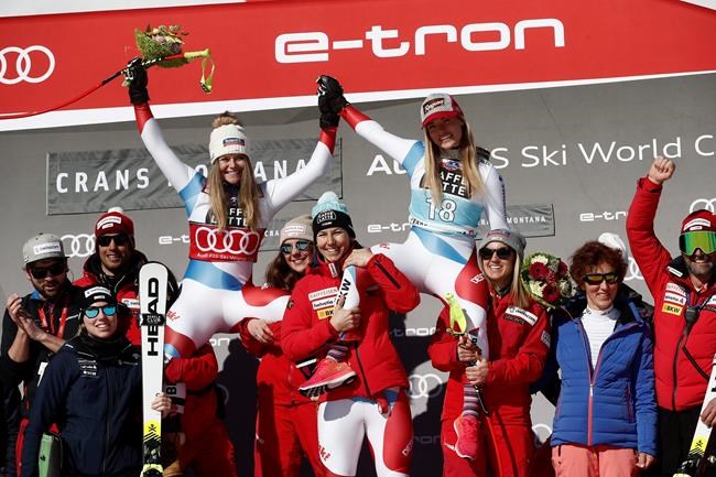 Switzerland's Lara Gut-Behrami, winner of an alpine ski, women's World Cup downhill, top right, celebrates with second-placed Switzerland's Corinne Suter, and the Swiss team, in Crans Montana, Switzerland, Friday, Feb. 21, 2020. (AP Photo/Gabriele Facciotti)