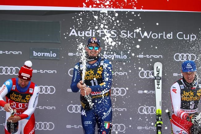 Italy's Dominik Paris, winner of an alpine ski, men's World Cup downhill, celebrates on the podium with second-placed Switzerland's Beat Feuz, left, and third-placed Austria's Matthias Mayer, in Bormio, Italy, Friday, Dec. 27, 2019. (AP Photo/Alessandro Trovati)