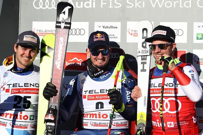 Italy's Dominik Paris, center, sits with Switzerland's Urs Kryenbuehl, left, and Switzerland's Beat Feuz at the finish area of an alpine ski, men's World Cup downhill, in Bormio, Italy, Saturday, Dec. 28, 2019. (AP Photo/Alessandro Trovati)