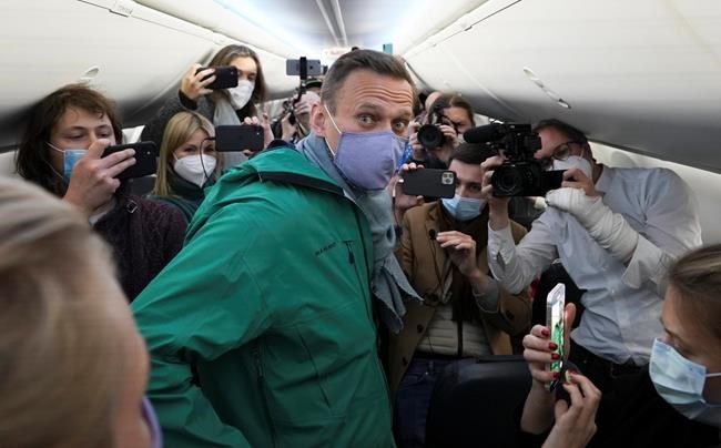 Alexei Navalny is surrounded by journalists inside the plane prior to his flight to Moscow in the Airport Berlin Brandenburg (BER) in Schoenefeld, near Berlin, Germany, Sunday, Jan. 17, 2021. Leading Kremlin critic Alexei Navalny plans to fly home to Russia on Sunday after recovering in Germany from his poisoning in August with a nerve agent. (AP Photo/Mstyslav Chernov)