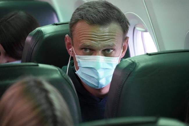 Alexei Navalny sits on the plane prior to a flight to Moscow, at the Airport Berlin Brandenburg (BER) in Schoenefeld, near Berlin, Germany, Sunday, Jan. 17, 2021. Leading Kremlin critic Alexei Navalny flew home to Russia on Sunday after recovering in Germany from his poisoning in August with a nerve agent. (AP Photo/Mstyslav Chernov)
