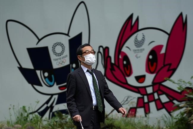 A man with a face mask against the spread of the new coronavirus walks in front of Miraitowa and Someity, mascots for the Tokyo 2020 Olympics and Paralympics at a park in Tokyo Tuesday, April 28, 2020. Japan's Prime Minister Shinzo Abe expanded a state of emergency to all of Japan from just Tokyo and other urban areas as the virus continues to spread. (AP Photo/Eugene Hoshiko)