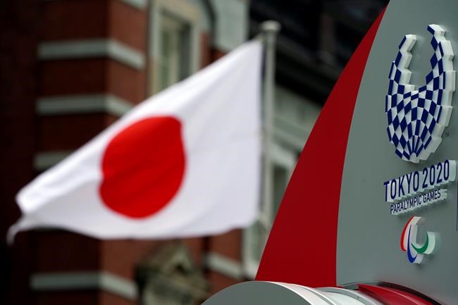A Japanese flag is seen near Tokyo 2020 Paralympic logo at Tokyo Station in Tokyo Tuesday, April 21, 2020. An open conflict broke out Tuesday between Tokyo Olympic organizers and the IOC over how much to divulge about who will pay for the unprecedented year-long postponement. (AP Photo/Eugene Hoshiko)