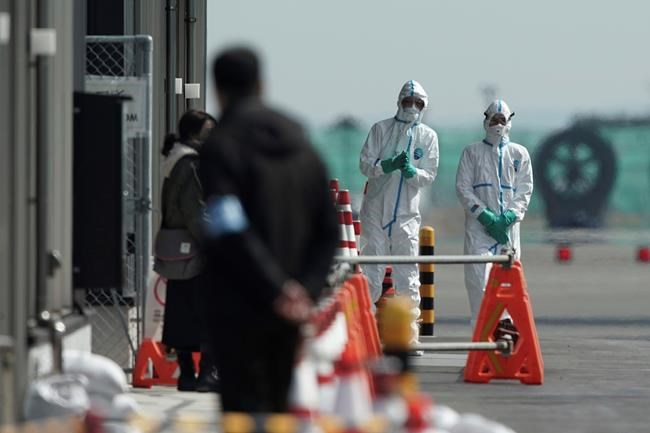 Officials in protective suits talk near the cruise ship Diamond Princess anchored at Yokohama Port in Yokohama, near Tokyo. Friday, Feb. 7, 2020. Japan on Friday reported 41 new cases of a virus on the cruise ship that's been quarantined. About 3,700 people have been confined aboard the ship. (AP Photo/Eugene Hoshiko)