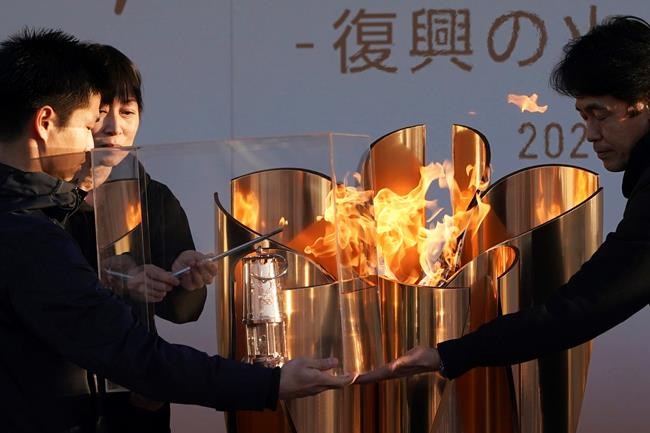 Officials light a lantern from the Olympic Flame at the end of a flame display ceremony in Iwaki, northern Japan, Wednesday, March 25, 2020. IOC President Thomas Bach has agreed