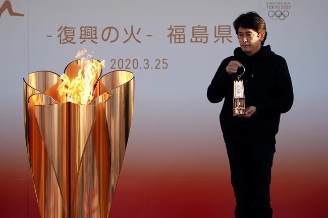 An official holds a lantern containing the Olympic Flame at the end of a flame display ceremony in Iwaki, northern Japan, Wednesday, March 25, 2020. IOC President Thomas Bach has agreed