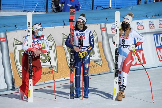 From left, second placed Switzerland's Lara Gut-Behrami, the winner Italy's Federica Brignone and third placed Switzerland's Corinne Suter, stand in the finish area after an alpine ski, women's World Cup super G, in Val di Fassa, Italy, Sunday, Feb. 28, 2021. (AP Photo/Elvis Piazza)