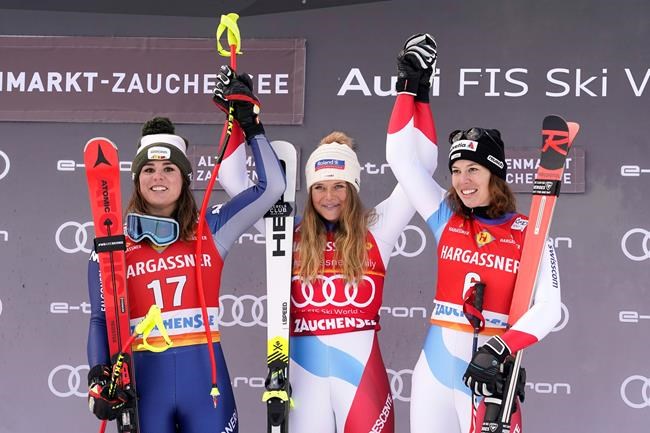 First placed Switzerland's Corinne Suter, center, second placed Italy's Nicol Delago, left, and third placed Switzerland's Michelle Gisin celebrate on the podium of an alpine ski, women's World Cup downhill, in Altenmarkt-Zauchensee, Austria, Saturday, Jan. 11, 2020. (AP Photo/Giovanni Auletta)