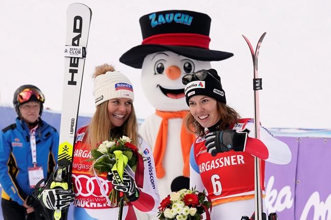 First placed Switzerland's Corinne Suter, left, and third placed Switzerland's Michelle Gisin pose for photos at the end of an alpine ski, women's World Cup downhill, in Altenmarkt-Zauchensee, Austria, Saturday, Jan. 11, 2020. (AP Photo/Giovanni Auletta)
