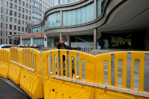 A security person waves away journalists outside the hotel where a team of experts from the World Health Organization are quarantined in Wuhan in centra China's Hubei province on Thursday, Jan. 28, 2021. A World Health Organization team has emerged from quarantine in the Chinese city of Wuhan to start field work in a fact-finding mission on the origins of the virus that caused the COVID-19 pandemic.(AP Photo/Ng Han Guan)