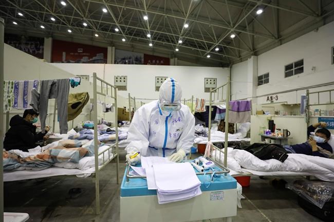 In this Feb. 18, 2020, photo, a medical staff member works near COVID-19 patients recuperating in a temporary hospital converted from an exhibition center in Wuhan in central China's Hubei province. The hospital, one of the dozen of its kind built in Wuhan, hosts COVID-19 patients with mild symptoms. (Chinatopix via AP)