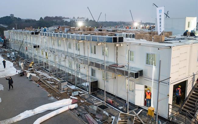 This Saturday, Feb. 1, 2020, photo released by China's Xinhua News Agency, shows construction workers at the site of the Huoshenshan temporary field hospital being built in Wuhan in central China's Hubei Province. China's death toll from a new virus has increased to 304 with more than 14,000 cases, amid warnings from the World Health Organization that other countries need to be prepared in the event the disease spreads among their populations. (Xiao Yijiu/Xinhua via AP)