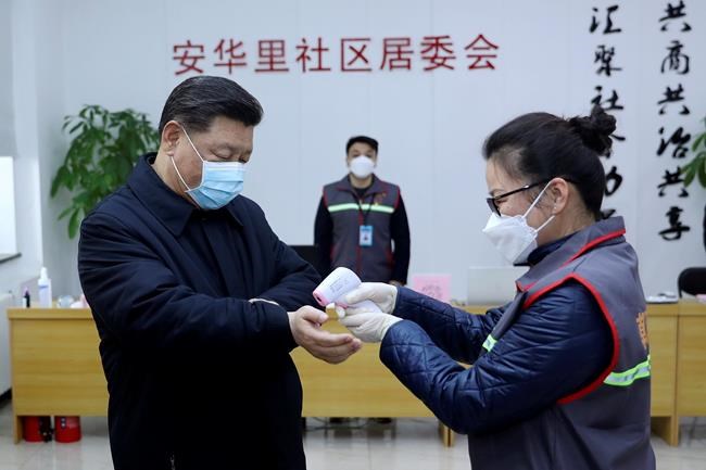 In this photo released by Xinhua News Agency, Chinese President Xi Jinping, left, wearing a protective face mask receives a temperature check as he inspects the novel coronavirus pneumonia prevention and control work at a neighbourhoods in Beijing, Monday, Feb. 10, 2020. China reported a rise in new virus cases on Monday, possibly denting optimism that its disease control measures like isolating major cities might be working, while Japan reported dozens of new cases aboard a quarantined cruise ship. (Pang Xinglei/Xinhua via AP)