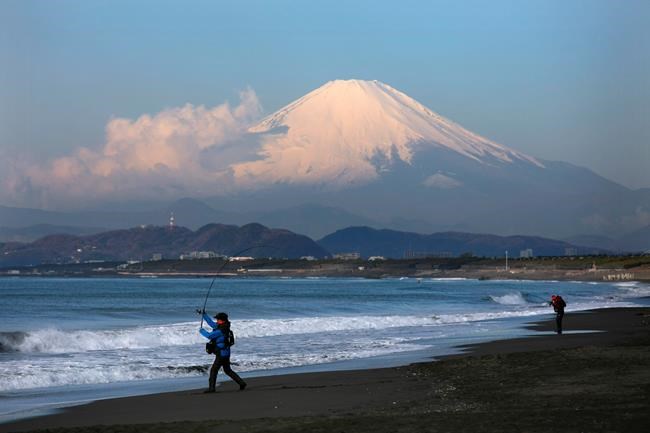 Backdropped by snow-capped Mount Fuji, a man casts his fishing rod into the ocean on a quiet beach in Fujisawa, Japan, Thursday, Feb. 27, 2020. According to local businesses in the area, the number of visitors has dropped significantly since the outbreak of COVID-19. (AP Photo/Jae C. Hong)