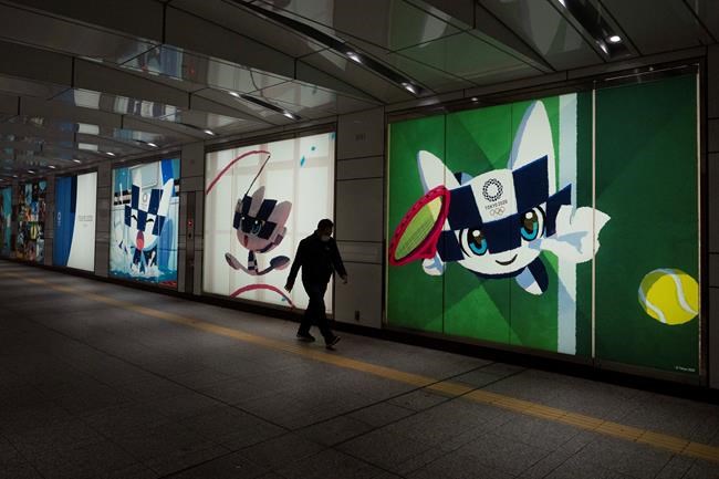 A man walks past large displays promoting the Tokyo 2020 Olympics in Tokyo, Tuesday, March 24, 2020. IOC President Thomas Bach has agreed