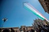 People gather to look at the Frecce Tricolori aerobatic squad of the Italian Air Force fly over Milan's Duomo cathedral, northern Italy, Monday, May 25, 2020 on the occasion of the 74th anniversary of the founding of the Italian Republic on June 2, 1946. This year the acrobatic squad will fly over several Italian cities to bring a message of unity and solidarity during the coronavirus pandemic.(AP Photo/Luca Bruno)