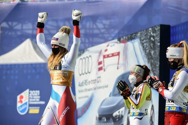 Switzerland's Corinne Suter celebrates on the podium after winning the gold medal in the women's downhill, at the alpine ski World Championships in Cortina d'Ampezzo, Italy, Saturday, Feb. 13, 2021. (AP Photo/Marco Tacca)