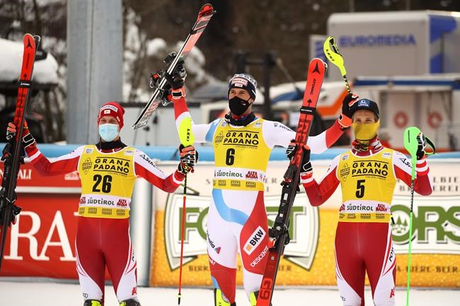 Switzerland's Ramon Zenhaeusern, center, winner, celebrates on the podium flanked by second place Austria's Manuel Feller, left, and third place Austria's Marco Schwarz after an alpine ski, men's World Cup slalom in Alta Badia, Italy, Monday, Dec.21, 2020. (AP Photo/MarcoTrovati)