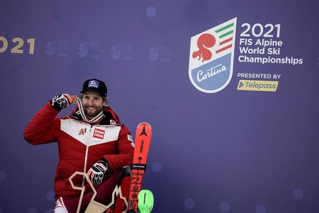 Austria's Marco Schwarz shows his gold medal for the men's combined race, at the alpine ski World Championships, in Cortina d'Ampezzo, Italy, Monday, Feb. 15, 2021. (AP Photo/Giovanni Auletta)