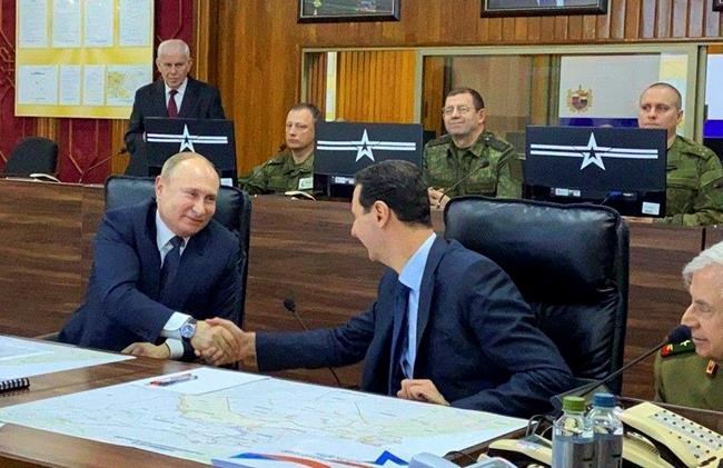This image released by the Syrian Presidency shows Russian President Vladimir Putin, left, meeting with Syrian President Bashar Assad, center, in Damascus, Syria on Tuesday, Jan. 7, 2020. Putin's visit is the second to the war-torn country where his troops have been fighting alongside Syrian government forces since 2015. (Syrian Presidency via AP)