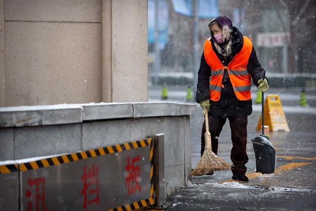 A maintenance worker wears a face mask as she sweeps snow during a snowfall in Beijing, Sunday, Feb. 2, 2020. China's death toll from a new virus increased to 304 on Sunday amid warnings from the World Health Organization that other countries need to prepare in the event the disease spreads among their populations as more nations report local infections. (AP Photo/Mark Schiefelbein)