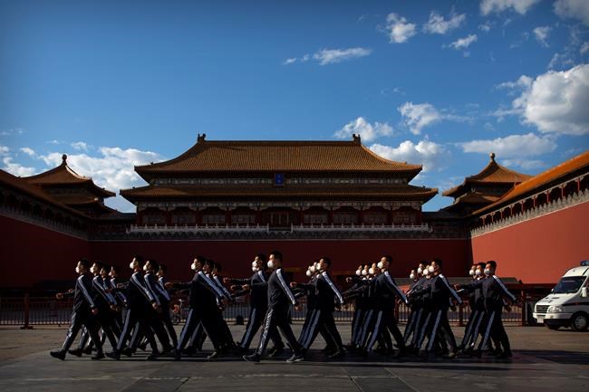 Plainclothes military personnel wearing face masks to protect against the new coronavirus march in formation outside the entrance to the Forbidden City in Beijing, Wednesday, May 27, 2020. The Chinese People's Political Consultative Conference (CPPCC) concluded its session in Beijing on Wednesday, part of the annual meetings of China's two top legislative bodies. (AP Photo/Mark Schiefelbein)
