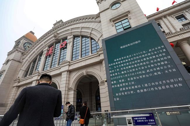 People walk past a billboard announcing the closure of the Hankou Railway Station in Wuhan in central China's Hubei Province, Thursday, Jan. 23, 2020. China closed off a city of more than 11 million people Thursday in an unprecedented effort to try to contain a deadly new viral illness that has sickened hundreds and spread to other cities and countries amid the Lunar New Year travel rush. (Chinatopix via AP)