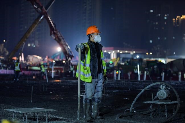 In this Tuesday, Jan. 28, 2020 photo, a construction worker rests at the site of the Huoshenshan temporary field hospital being built in Wuhan in central China's Hubei Province. China as of Wednesday has more infections of a new virus than it did in with SARS, though the death toll is still lower. (Chinatopix via AP)