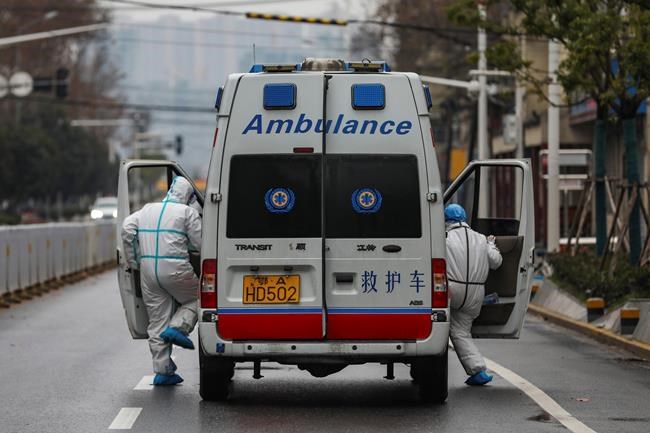 In this Sunday, Jan. 26, 2020 photo, ambulance crew members in protective gear get into their ambulance in Wuhan in central China's Hubei Province. A new viral illness being watched with a wary eye around the globe accelerated its spread in China on Sunday with 56 deaths so far, while the U.S. Consulate in the city at the epicenter announced it will evacuate its personnel and some private citizens aboard a charter flight. (Chinatopix via AP)