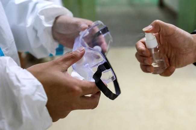 In this Sunday, Jan. 26, 2020 photo, medical workers spray disinfectant in goggles in Wuhan in central China's Hubei Province. A new viral illness being watched with a wary eye around the globe accelerated its spread in China on Sunday with 56 deaths so far, while the U.S. Consulate in the city at the epicenter announced it will evacuate its personnel and some private citizens aboard a charter flight. (Chinatopix via AP)