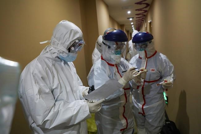 A medical worker in a protective suit writes on a tube after collecting a sample for nucleic acid tests from a suspected virus patient at a hotel being used to place people in medical isolation in Wuhan in central China's Hubei Province, Tuesday, Feb. 4, 2020. Hong Kong hospitals cut services as thousands of medical workers went on strike for a second day Tuesday to demand the border with mainland China be shut completely, as a new virus caused its first death in the semi-autonomous territory and authorities feared it was spreading locally. (Chinatopix via AP)
