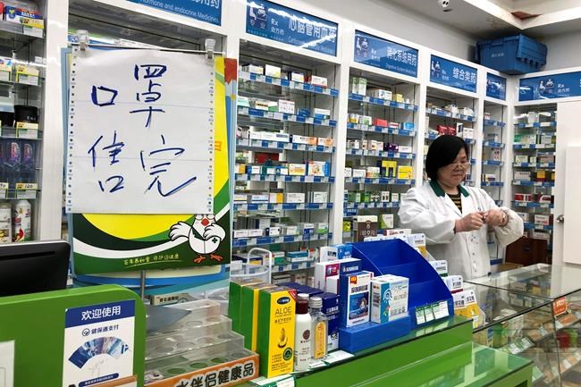 Pharmacist Liu Zhuzhen stands near a sign reading