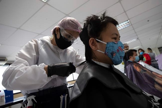 In this Tuesday, April 28, 2020, photo, Pornsupa Hattayong gives haircuts to a medical worker treating COVID-19 patients for free at Bangkok Metropolitan Administration General Hospital in Bangkok, Thailand. The 43-year-old hairstylist is boosting the morale of frontline medical workers by dispensing free haircuts at Bangkok hospitals since Thailand’s hair salons have been closed for more than a month, to help stop the spread of the coronavirus. (AP Photo/Sakchai Lalit)
