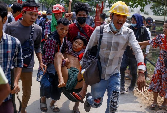 Anti-coup protesters carry an injured man following clashes with security in Yangon, Myanmar Sunday, March 14, 2021. The civilian leader of Myanmar's government in hiding vowed to continue supporting a