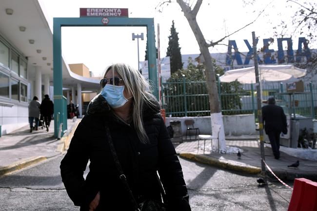A woman wearing a face mask exits from AHEPA hospital in the northern port city of Thessaloniki, Greece, Wednesday, Feb. 26, 2020. Greek authorities have confirmed the country's first case of the new conronavirus. The health ministry's head of infectious diseases, Sotiris Tsiodras, said the case was a 38-year-old woman in Thessaloniki who had recently traveled to northern Italy. (AP Photo/Giannis Papanikos)