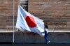 An athlete adjusts the Japanese flag during the Olympic flame handover ceremony for the 2020 Tokyo Summer Olympics, in Athens, Thursday, March 19, 2020. The ceremony was held behind closed doors and with the presence of few members of the media because of fears over the new coronavirus. (Aris Messinis/Pool via AP)