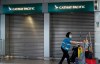 A cleaner walks past a Cathay Pacific booth at the airport train station in Hong Kong Wednesday, Oct. 21, 2020. Hong Kong airline Cathay Pacific Airways on Wednesday said it would cut 8,500 jobs and shut down its regional airline unit in a corporate restructuring, as it grapples with the plunge in air travel due to the pandemic. (AP Photo/Vincent Yu)