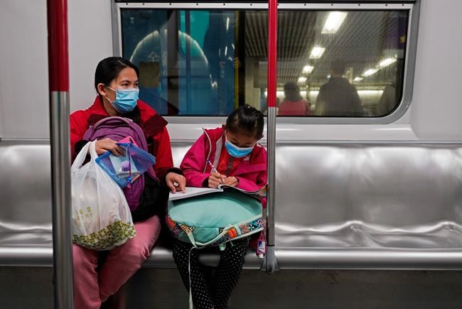 A girl wears a protective face mask as she does homework at a subway train in Hong Kong, Friday, Jan. 31, 2020. The World Health Organization declared the outbreak sparked by a new virus in China that has spread to more than a dozen countries a global emergency after the number of cases spiked more than tenfold in a week, including the highest death toll in a 24-hour period reported Friday. (AP Photo/Vincent Yu)