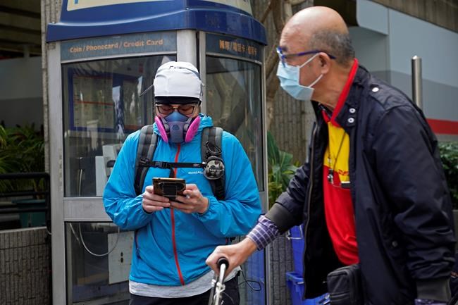 People wear face masks at a street in Hong Kong Tuesday, Feb. 25, 2020. COVID-19 viral illness has sickened tens of thousands of people in China since December. (AP Photo/Vincent Yu)