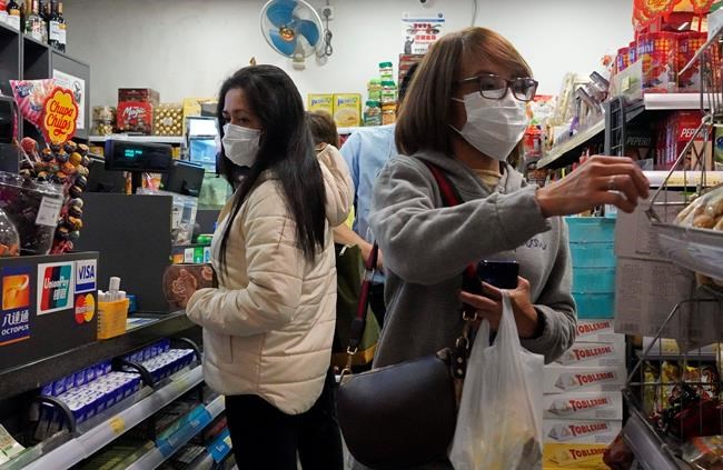 People wear protective face masks as they make purchases from a convenience store in Hong Kong, Monday, Feb, 3, 2020. Lam says the city will shut almost all land and sea border control points to the mainland from midnight to stem the spread of the novel coronavirus from China. (AP Photo/Vincent Yu)