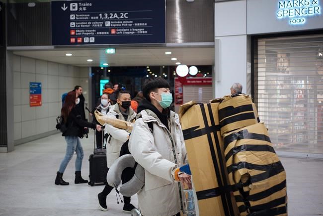Travelers from Beijing , wearing masks, arrive at Charles de Gaulle airport, north of Paris, early Monday, Jan. 27, 2020. France's government announced Sunday it will repatriate up to hundreds of French citizens from the Chinese city of Wuhan, the epicenter of a deadly new virus. (AP Photo/Kamil Zihnioglu)