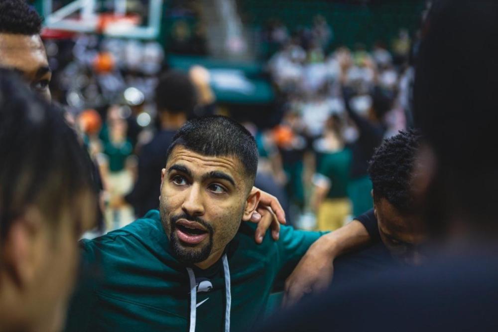 - Cara Kaye/Creative Director at Michigan State University
Manny Dosanjh photographed in a Michigan State huddle. He is making history as the first Canadian of Indian descent to hold an assistant coach job at the NCAA.
