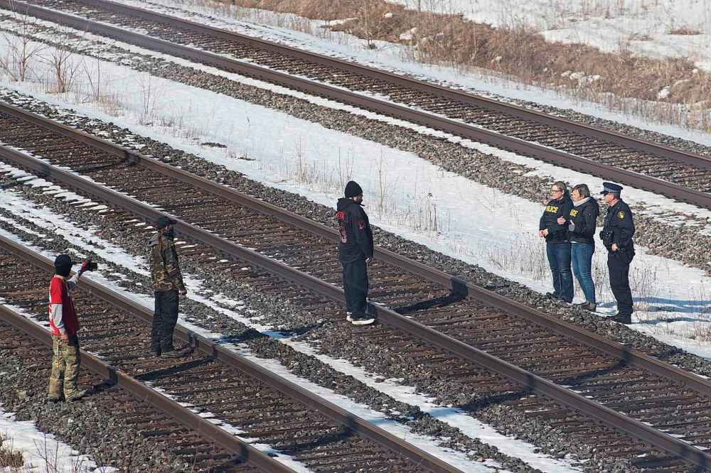 Ontario Provincial Police liaison officers speak with protesters on the closed train tracks at a second rail blockade in Tyendinaga Mohawk Territory, near Belleville, Ont., on Monday. THE CANADIAN PRESS/Lars Hagberg