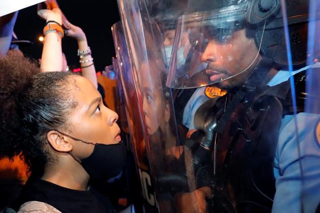 A protester and a police officer stare at one another on the Crescent City Connection bridge, which spans the Mississippi River in New Orleans, Wednesday, June 3, 2020, during a protest over the May 25 death of George Floyd, who died after being restrained by police in Minneapolis. (AP Photo/Gerald Herbert)