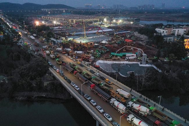 In this Tuesday, Jan. 28, 2020, photo, construction trucks are lined up at the site of the Huoshenshan temporary field hospital being built in Wuhan in central China's Hubei Province. China as of Wednesday has more infections of a new virus than it did in with SARS, though the death toll is still lower. (Chinatopix via AP)