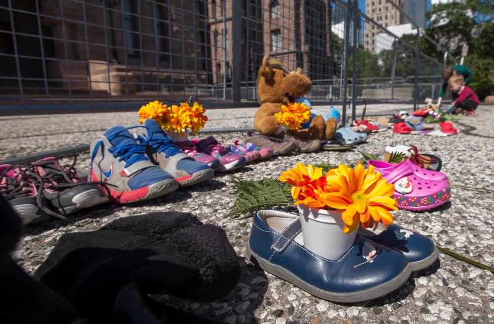 Rick Madonik - Toronto Star
Two small boys leave shoes at a small memorial honouring the recently discovered mass grave at the Kamlooops Residential School in front of Queen's Park Legislative building in Toronto.