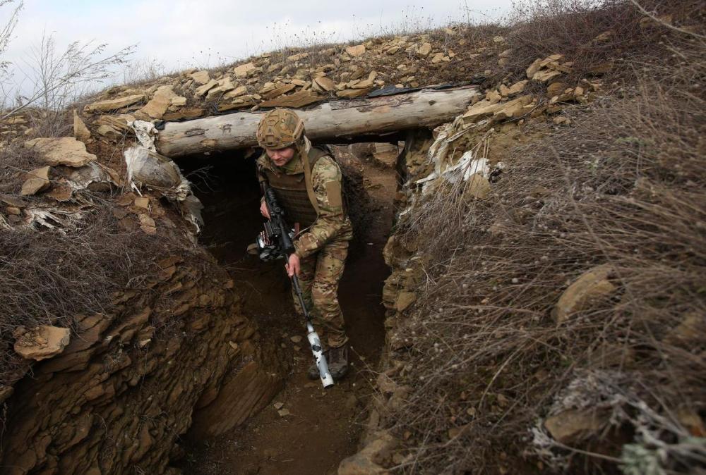 ANATOLII STEPANOV - AFP via GETTY IMAGES
A Ukrainian serviceman walks along a trench at a position on the front line with Russia-backed separatists near the settlement of Troitske in the Lugansk region on Feb. 22, 2022, a day after Russia recognized east Ukraine's separatist republics and ordered the Russian army to send troops there as “peacekeepers.”